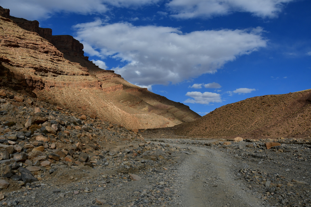 Piste ueber Steine Berge Wolken