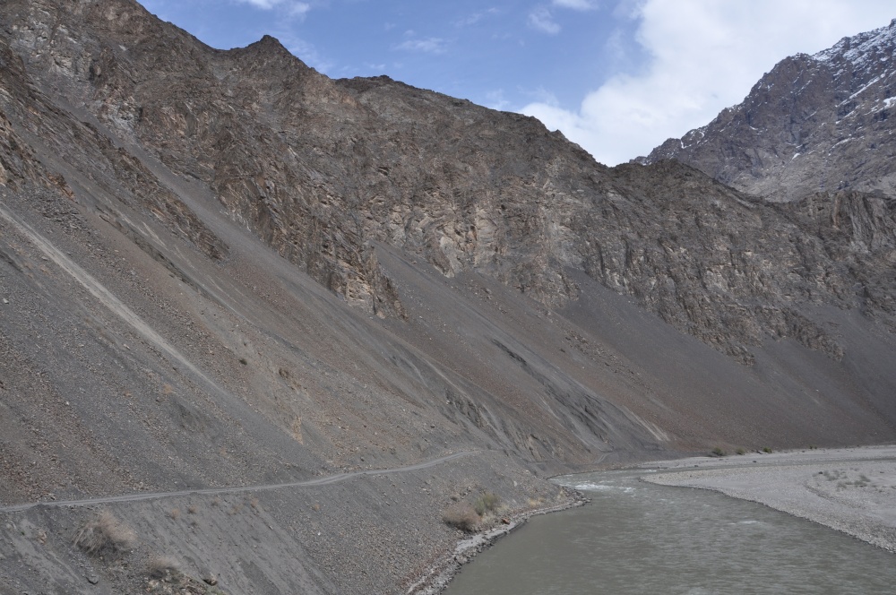 Piste entlang des Flusses unterhalb felsiger Berge